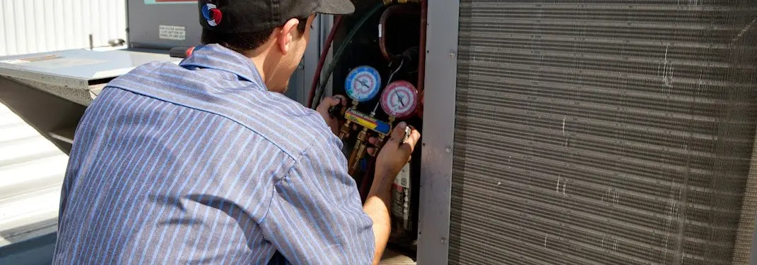 HVAC technician servicing a condenser unit in Evergreen